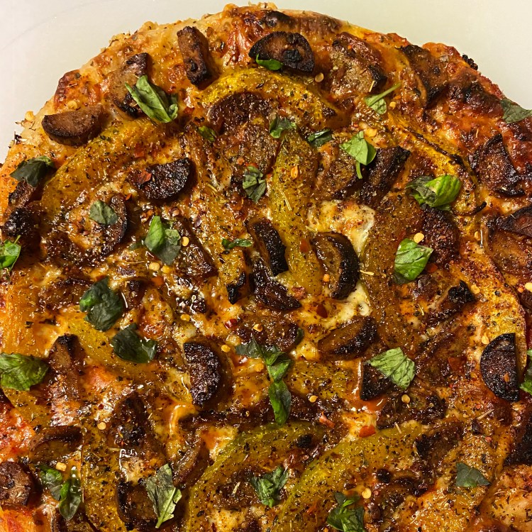 closeup of an uncut pizza with the toppings listed in the caption plus lots of cheese