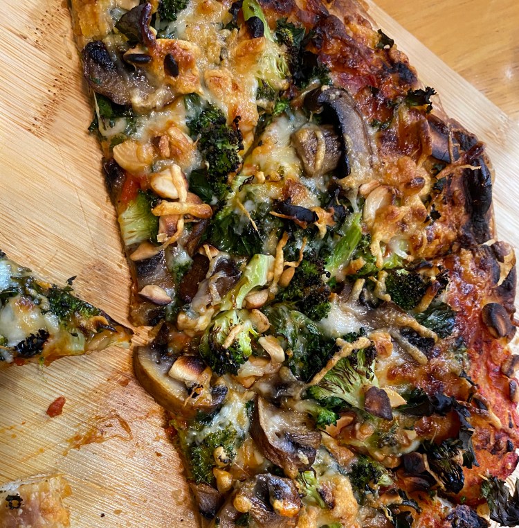 a cut pizza on a wood board with the toppings listed in the caption plus lots of cheese