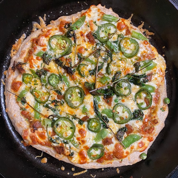 an uncut pizza in a black cast iron pan with the toppings listed in the caption plus lots of cheese