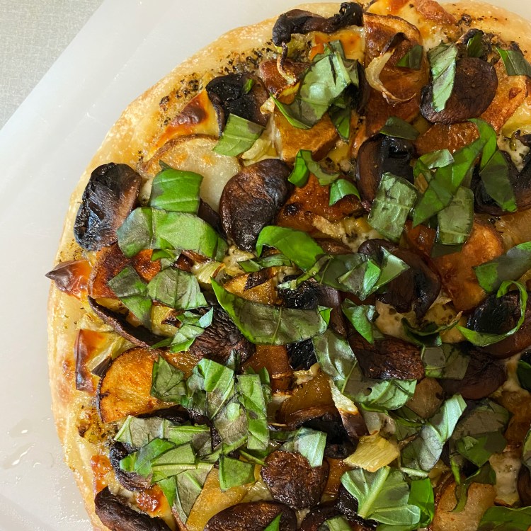 closeup of an uncut pizza with the toppings listed in the caption