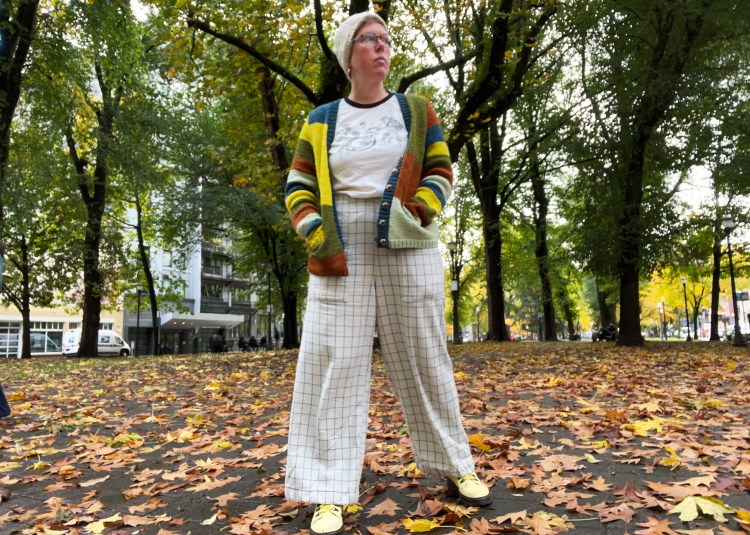 Lee wearing cardigan outside, unbuttoned with hands in pockets and wide-leg pants