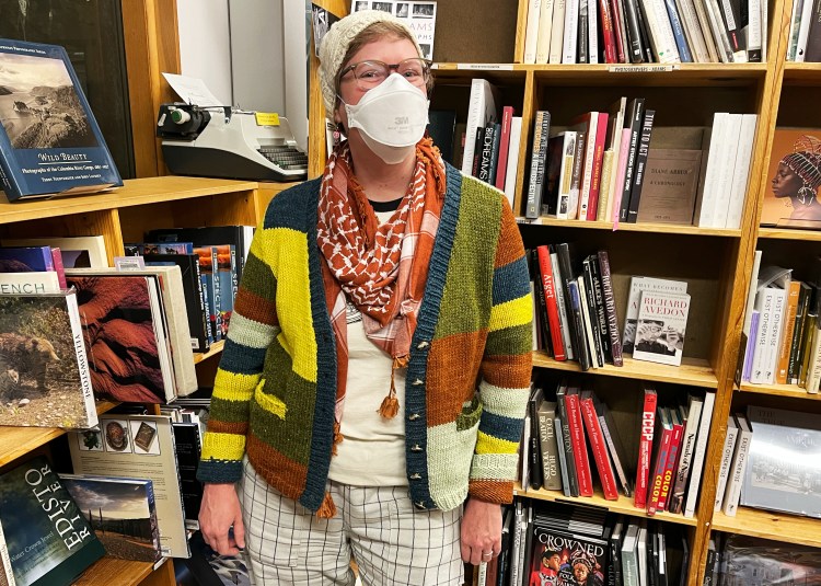 Lee wearing cardigan in a bookstore