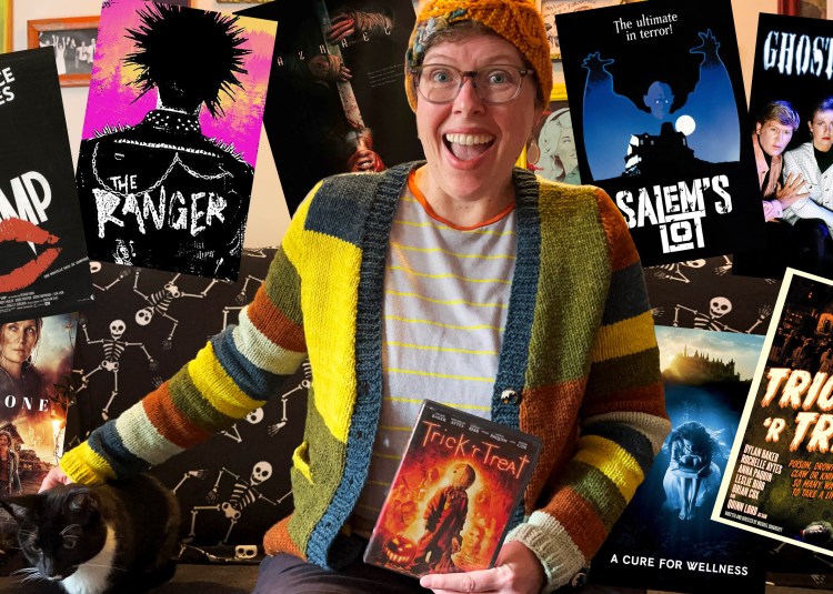 image of Lee wearing finished cardigan petting a tuxedo cat and poster images of 7 movies and holding the Trick r Treat dvd