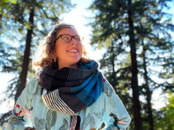 Lee wearing a worsted weight cowl double-wrapped in blue, grey, white shades with wide stripes and 1x1 stripe segments blending between