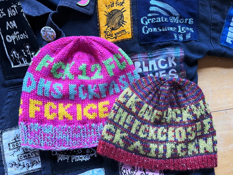 2 hats with words on them laying flat amongst related items (jacket with patches)—visible words are FCK 12, FCK ICE, FCK CEOS
