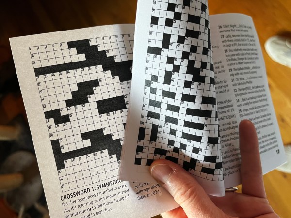 hand holding a zine open with two pages showing, both with crosswords
