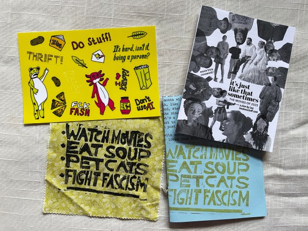 4 items laying flat: a sticker sheet with hand-drawn stickers on a yellow background, zine "it's just like that sometimes: the movies of 2025, a zine by Lee leedoesstuff.com", patch on greenish yellow fabric that says "watch movies, eat soup, pet cats, fight fascism", and blue paper with stamped on print same as patch