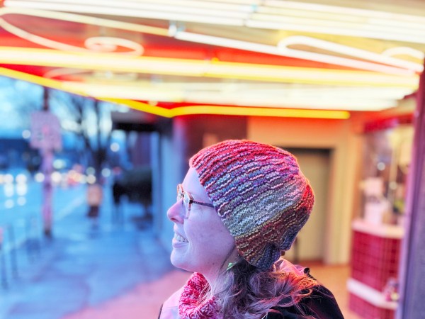 Lee standing under neon lights wearing a Wowee Zowee hat